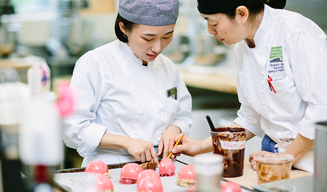 A AVԴbaking instructor and student look over pink pastries